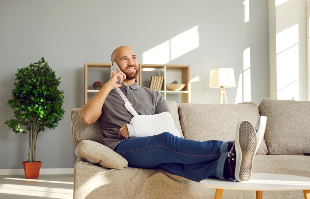 Photo of a man sitting on the couch with arm banded