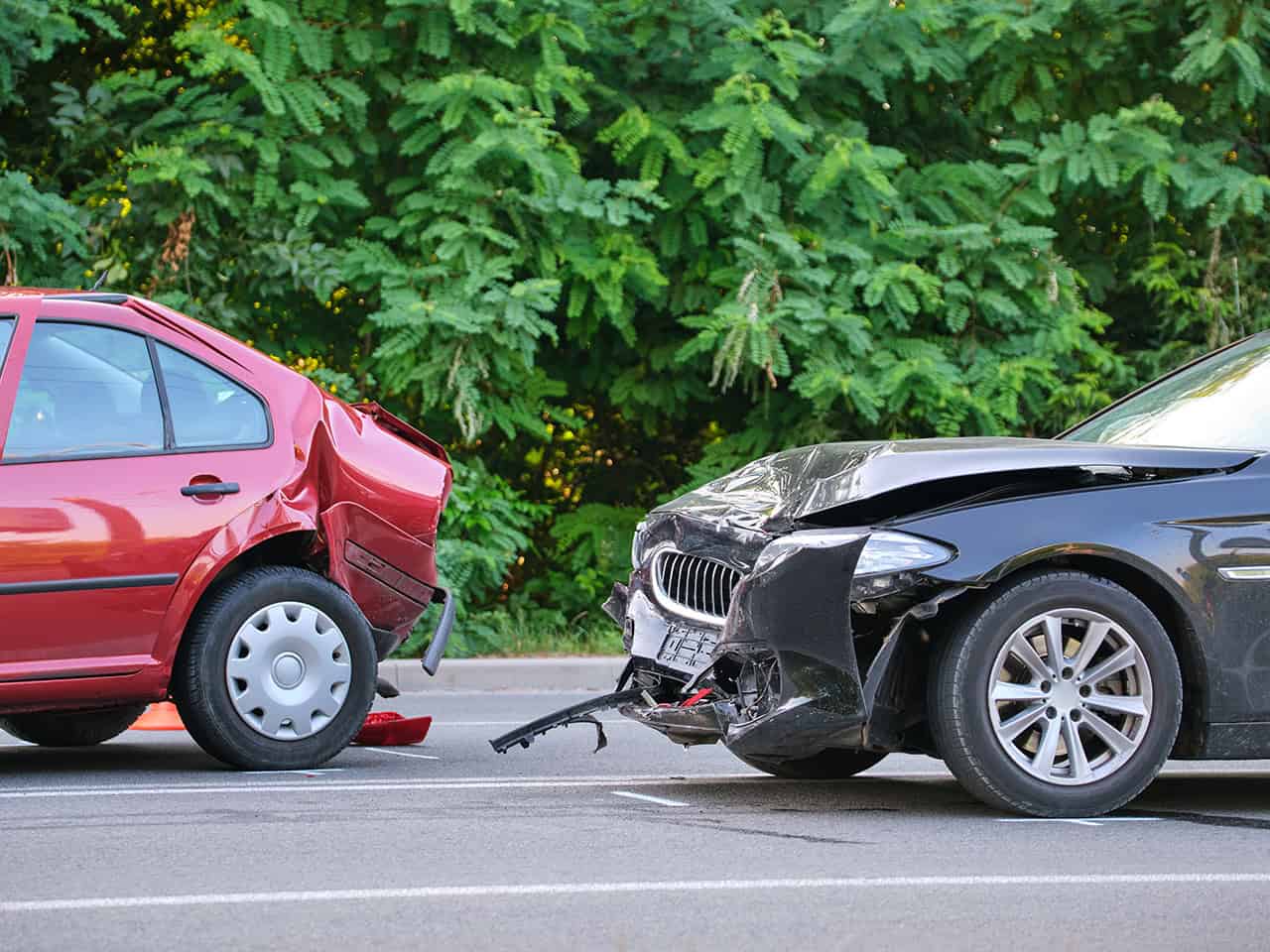 car accident scene where black car rear ends a red car