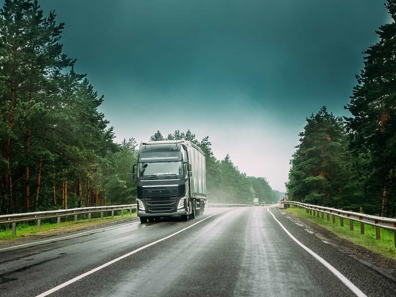 Tractor trailer driving on tree lined road