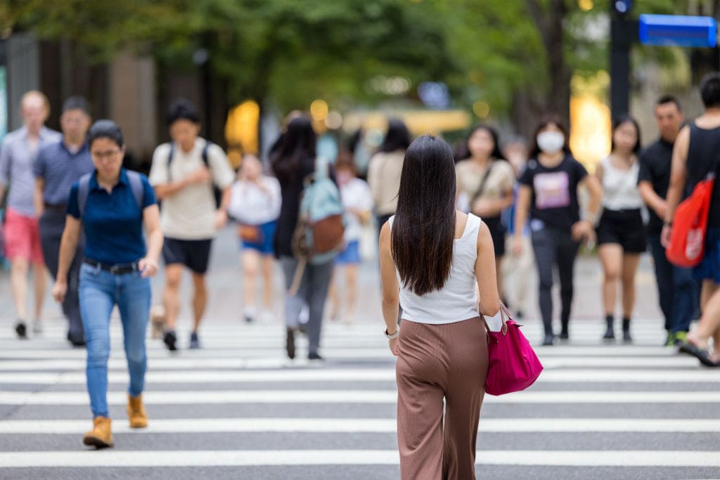 Woman walking on crowded city crosswalk