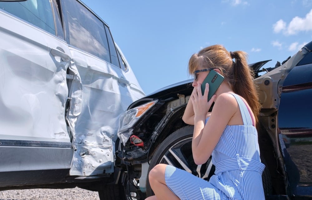 Woman On Phone Looking At A Crashed Car